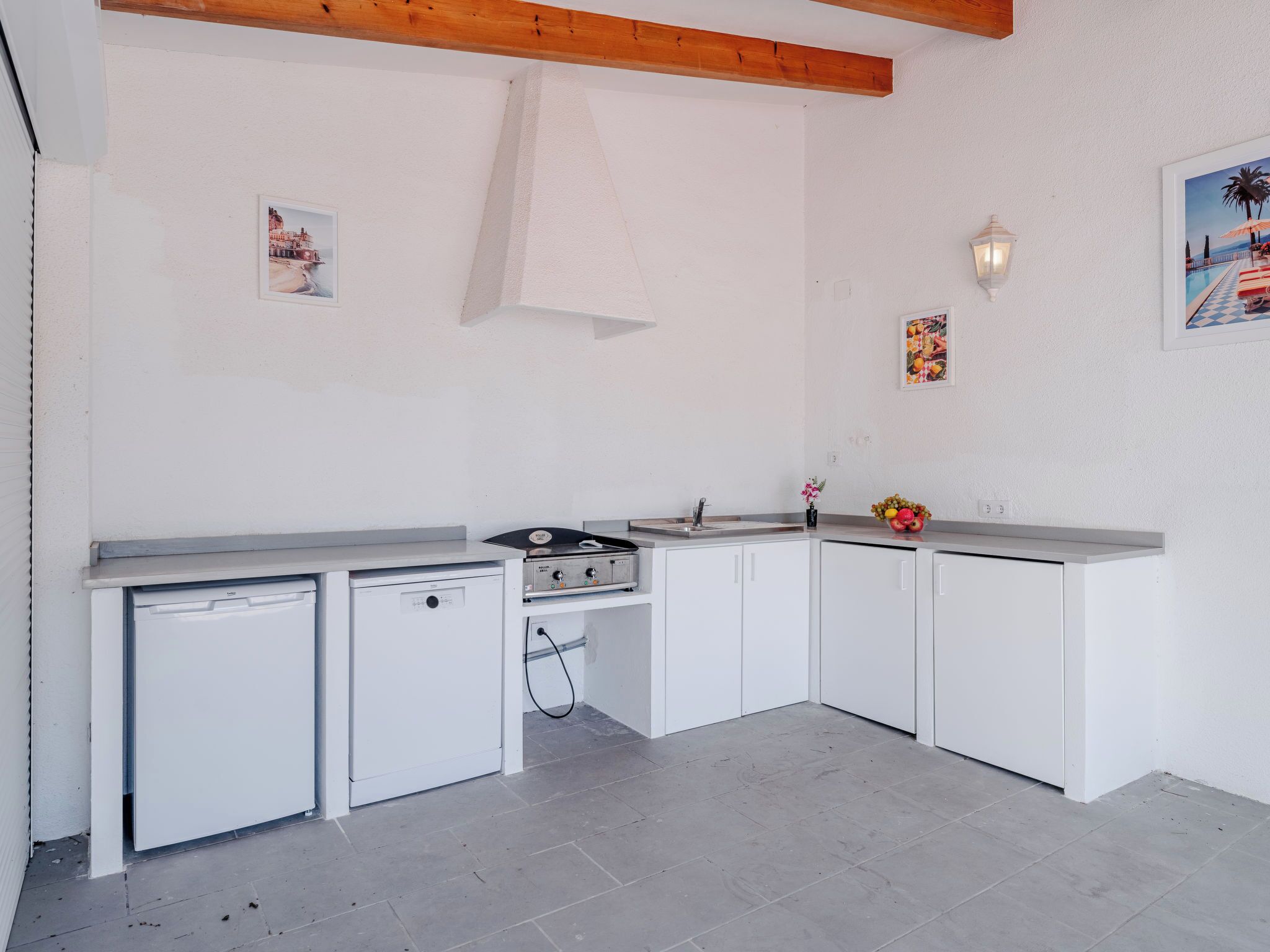 A compact kitchen with white cabinets, a small refrigerator, a gas stove, and a sink.