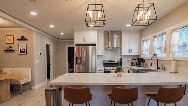 Una cocina moderna con una isla grande, electrodomésticos de acero inoxidable e iluminación colgante.