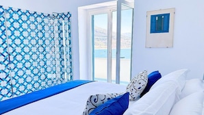 Una habitación con una cama, un ventanal y una cortina estampada.