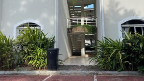 Un immeuble doté de nombreux balcons, de climatiseurs et d’un chemin en briques menant à l’entrée.