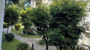 Une cour avec un chemin de pierre, une végétation luxuriante et des bâtiments en arrière-plan.