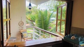 Une cuisine donnant sur un balcon, avec un luminaire suspendu et une chaise dotée d’un coussin.