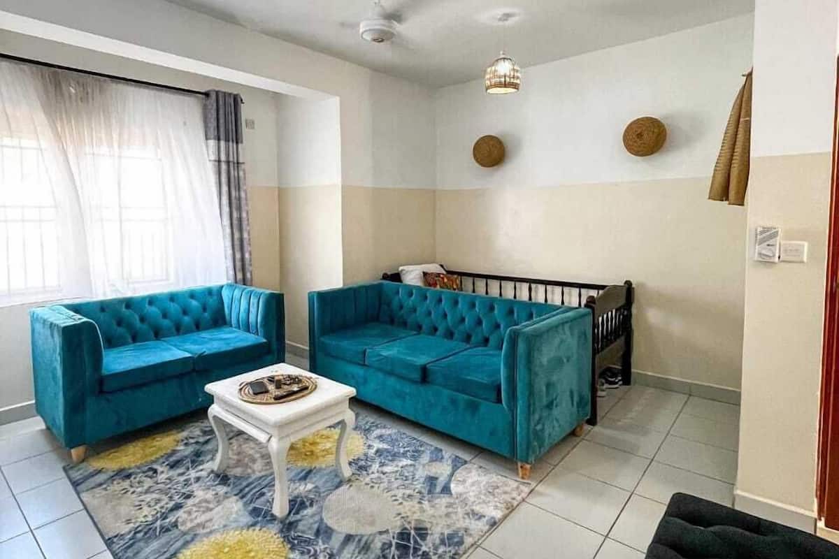 A living room with two blue sofas, a white coffee table, and a patterned rug.