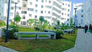 Un moderno edificio residenziale con balconi, un vialetto lastricato e zone relax all'aperto.