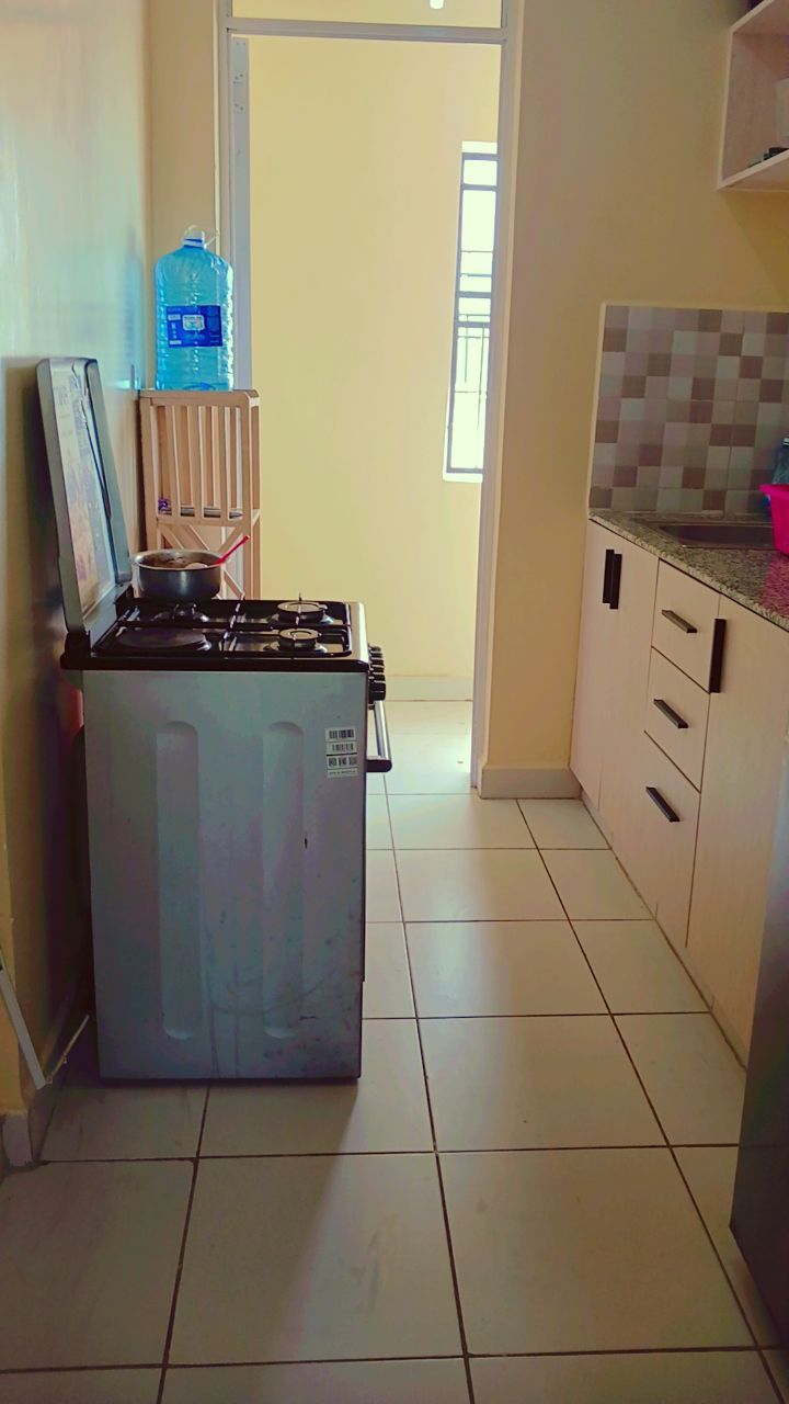 A kitchen with a gas stove, a water dispenser, and tiled flooring.