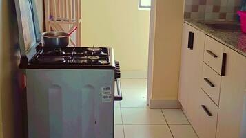 A kitchen with a gas stove, a water dispenser, and tiled flooring.