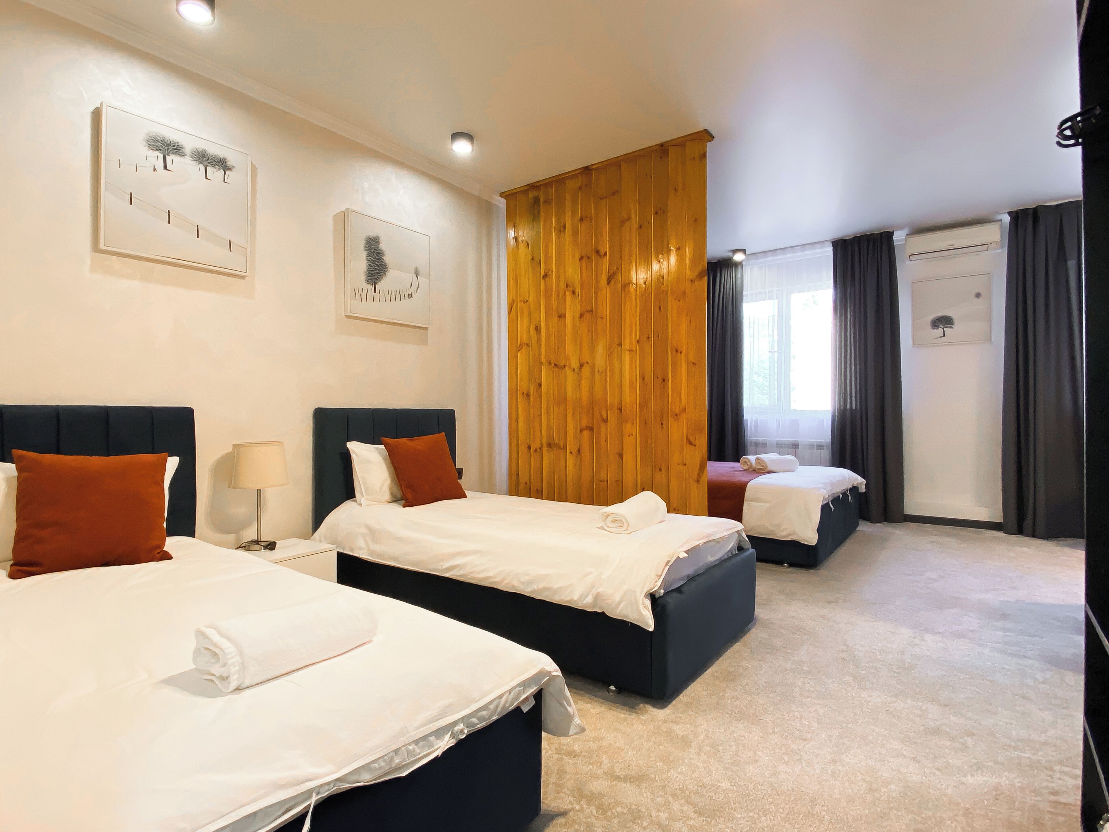 A hotel room with two beds, a wooden partition, and artwork on the walls.