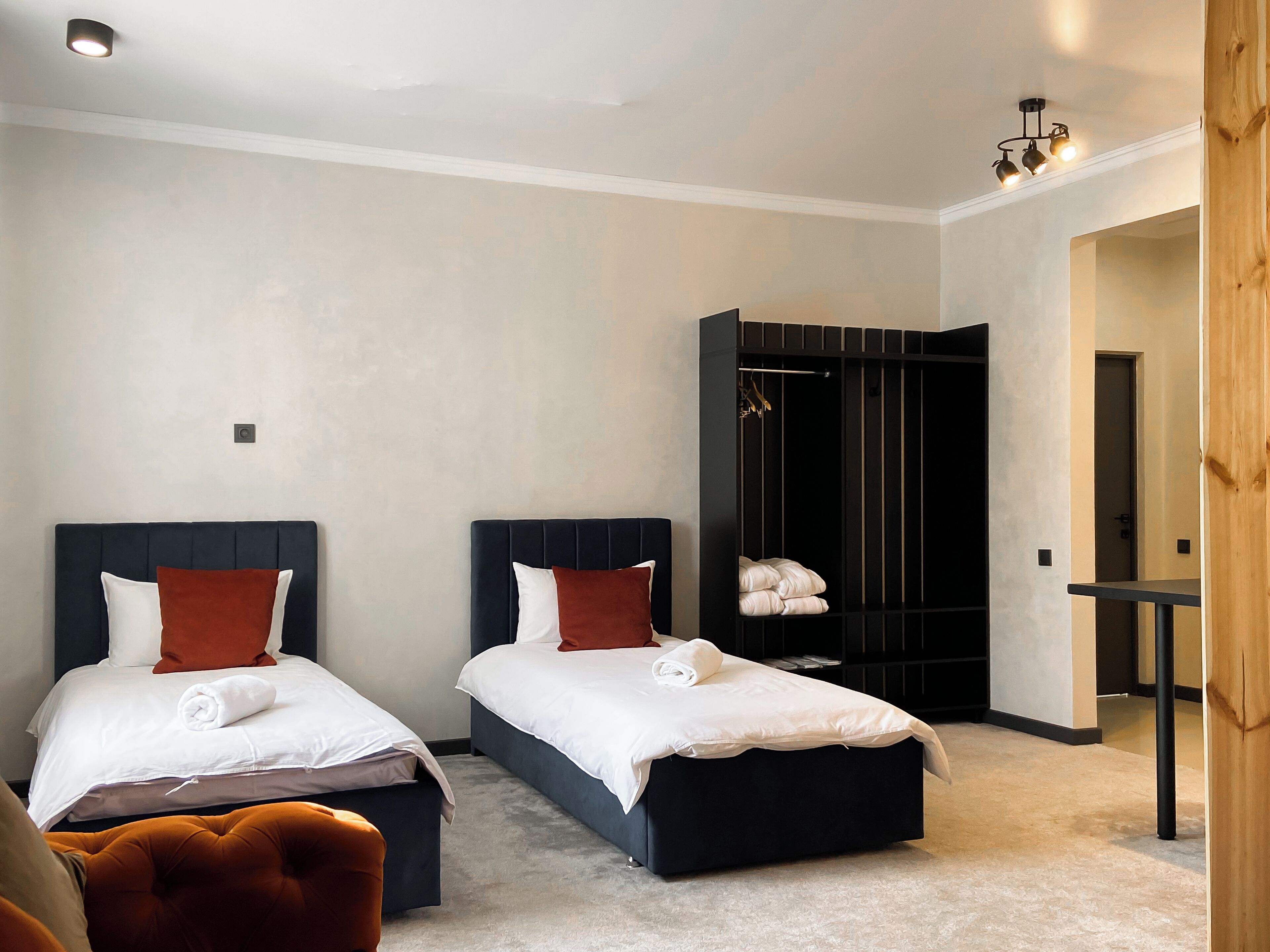 A hotel room with two beds, a wardrobe, and a small table.