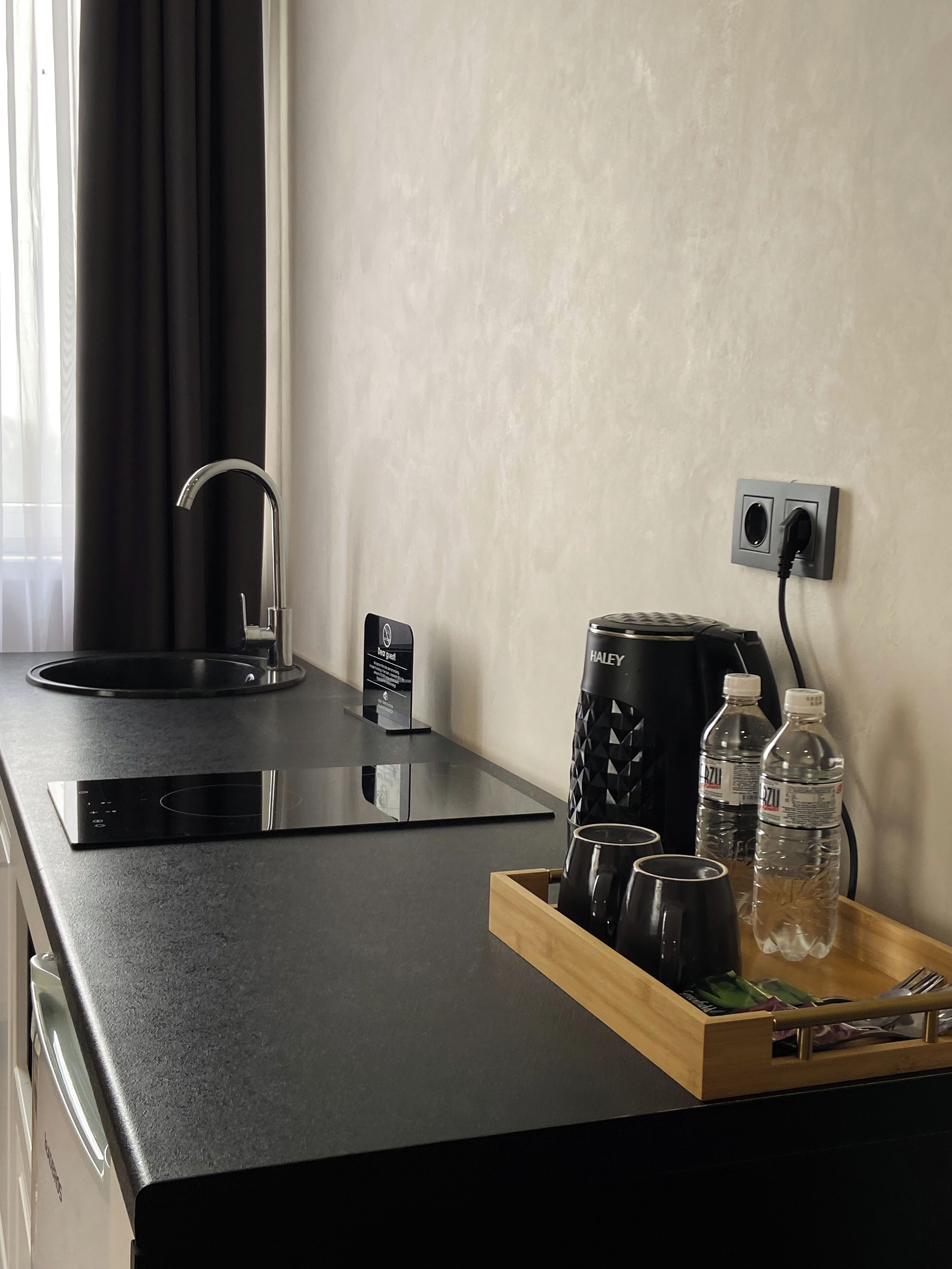 A modern kitchen with a black countertop, a kettle, a coffee maker, a kettle, and a water bottle.