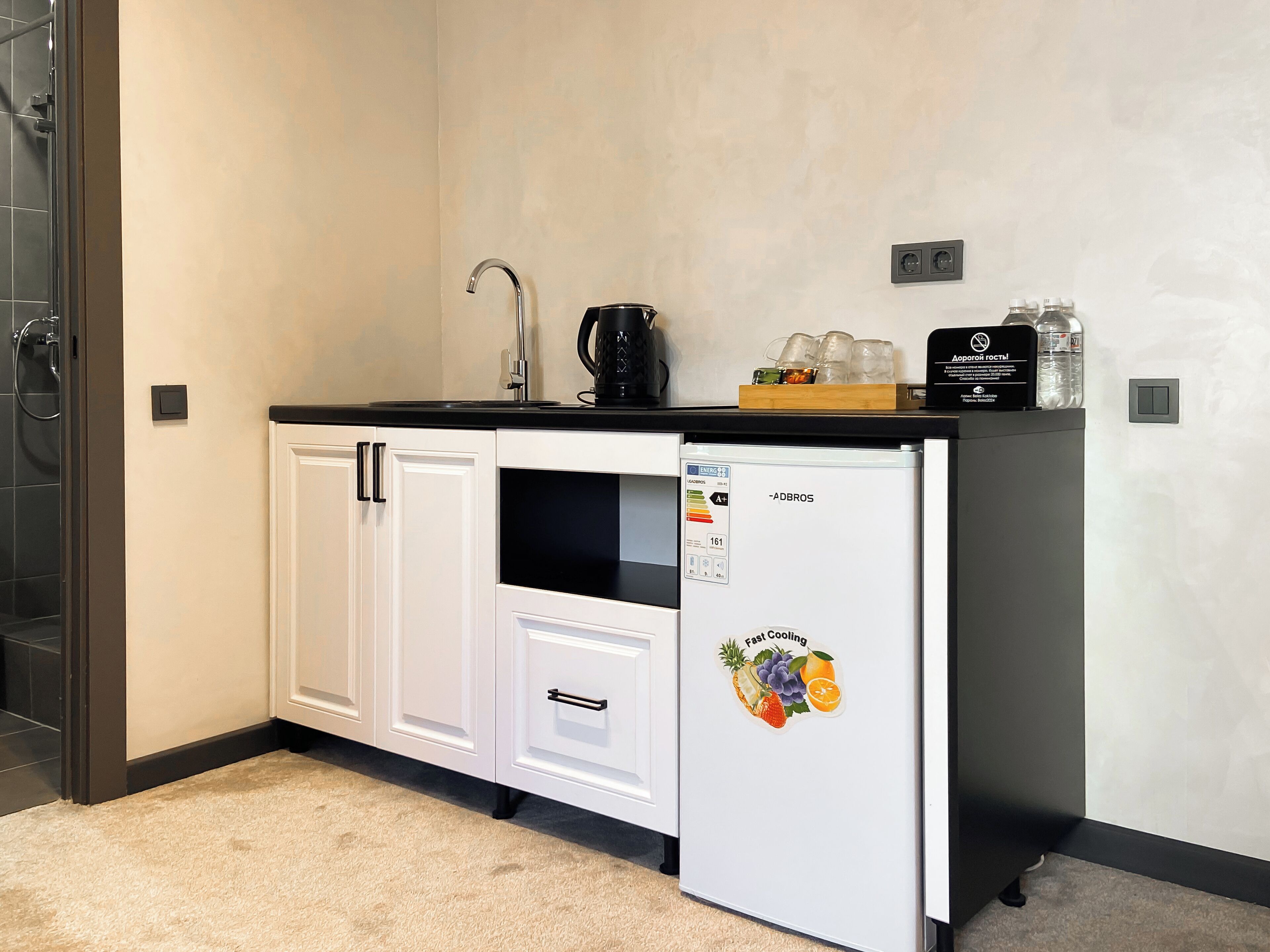 A compact kitchenette with a refrigerator, a coffee maker, and a water dispenser.