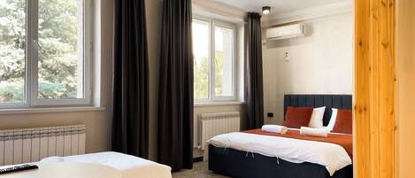 Una habitación de hotel con dos camas, un escritorio y una ventana con cortinas.