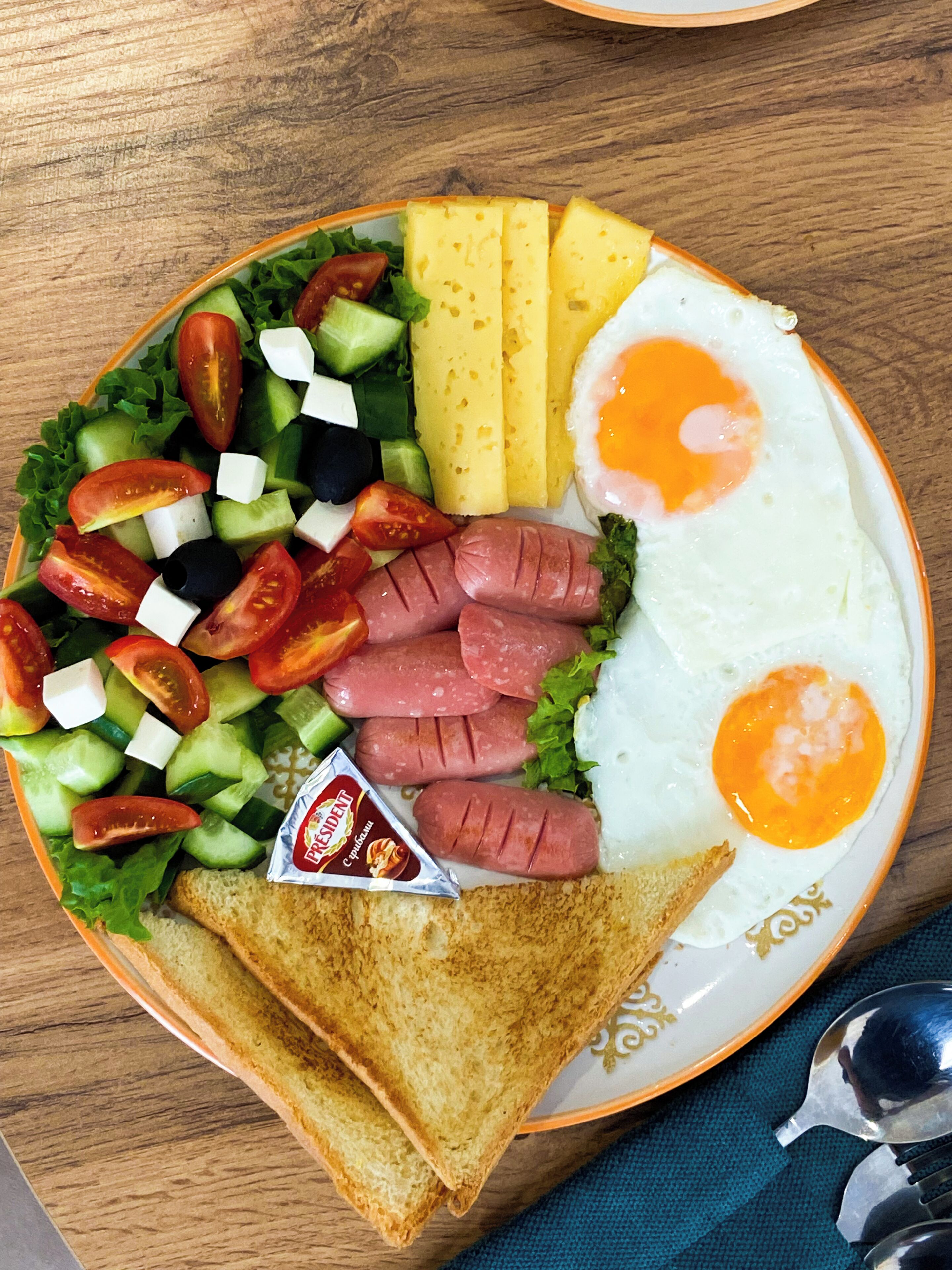 Ein Teller mit Eiern, Würstchen, Käse und Gemüse.