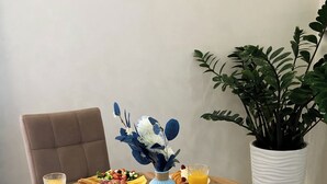 A round wooden dining table with plates of food, cups, and a vase with flowers. - Beles Apartments (Almaty)