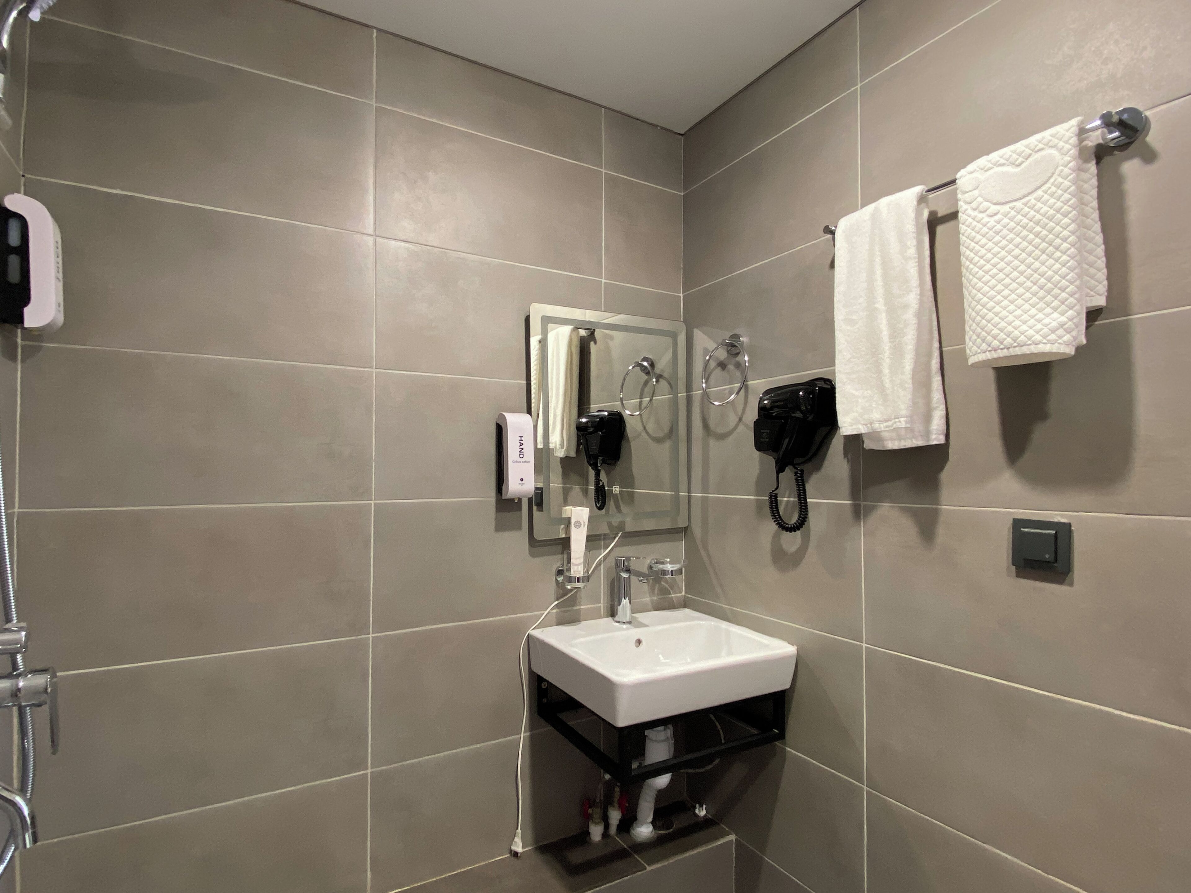 A modern bathroom with a white sink, a handheld hair dryer, and a towel rack.