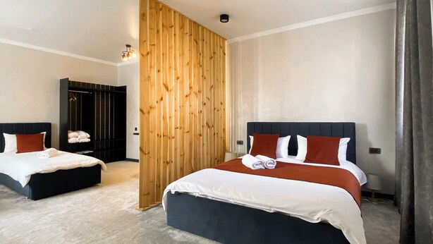 A hotel room with two beds, a wooden partition, and a wardrobe. - Beles Apartments (Almaty)