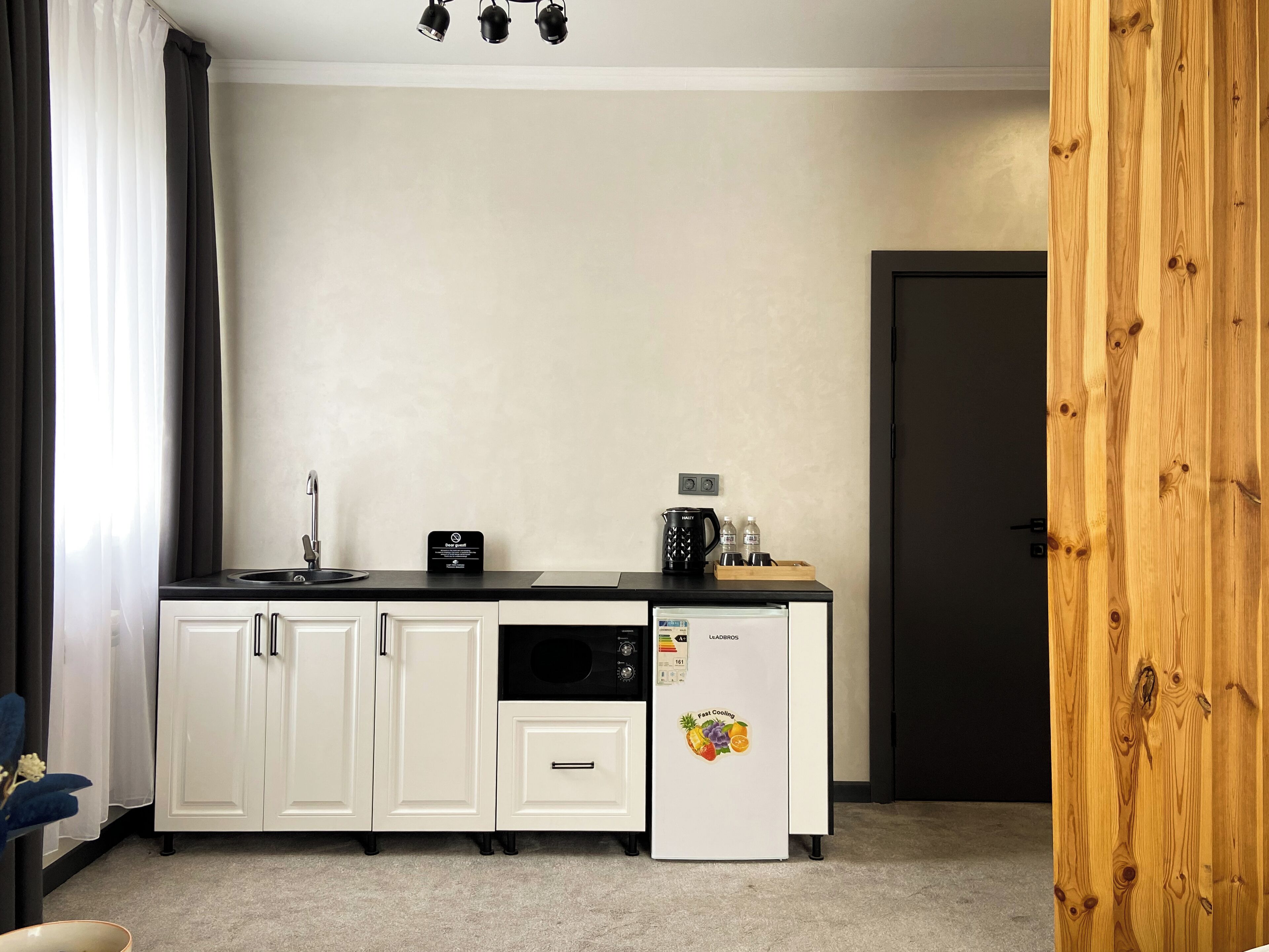 A compact kitchenette with a refrigerator, microwave, and coffee maker.