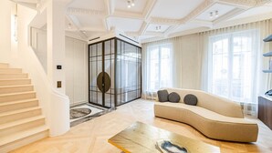 A spacious living room with a curved sofa, a wooden coffee table, and a glass partition. - Hôtel  Particulier#Monceau#5 Chambres #Grand luxe (Paris)