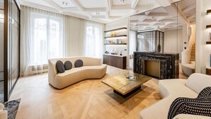 A spacious living room with a curved sofa, a coffee table, and a fireplace. - Hôtel  Particulier#Monceau#5 Chambres #Grand luxe (Paris)