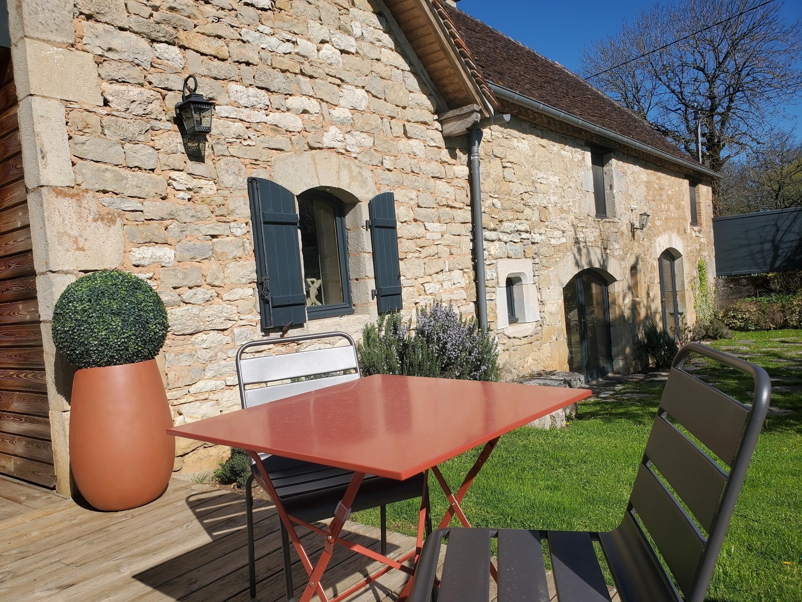 A stone building with a wooden deck, a table, and a chair.