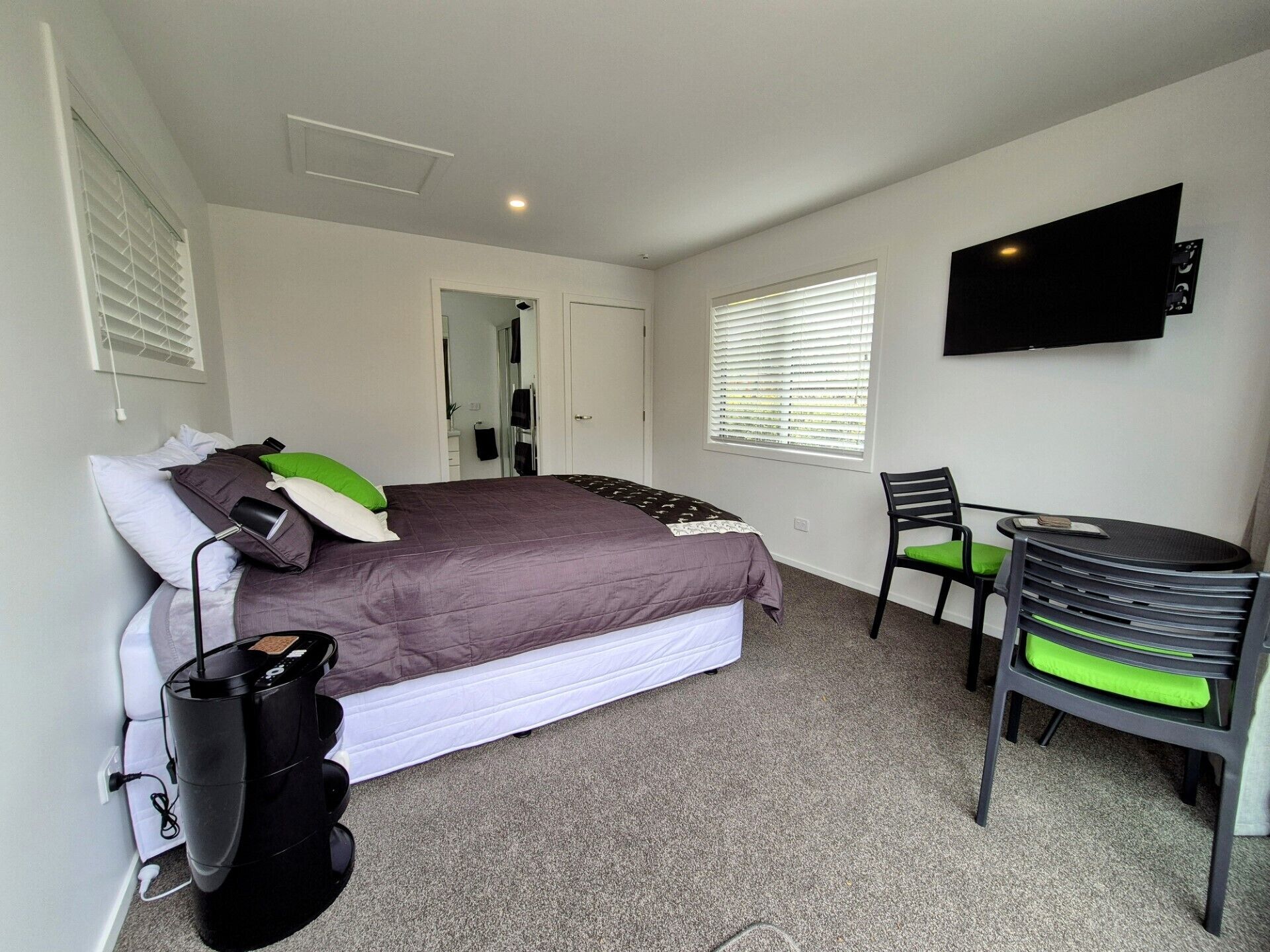 Un dormitorio con cama, escritorio, silla y televisor en la pared.