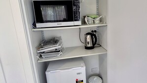 A compact kitchenette with a microwave, kettle, and refrigerator on shelves. - Private Studio - Perfect for short stays in Taupo. (Taupo)