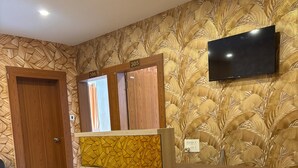 Un comptoir d’accueil avec un revêtement en bois et un panneau décoré d’un motif jaune. Un téléviseur à écran plat est fixé au mur, au-dessus du comptoir.