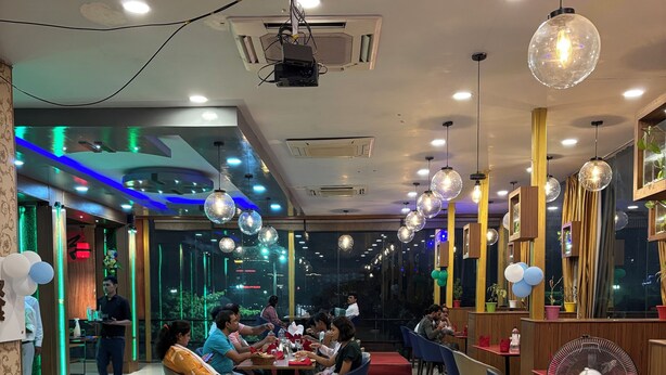 Un restaurant avec des tables et des chaises, un ventilateur et des éclairages décoratifs.