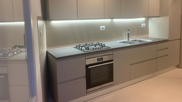 Een moderne keuken met een gasfornuis, oven en een roestvrijstalen spoelbak.