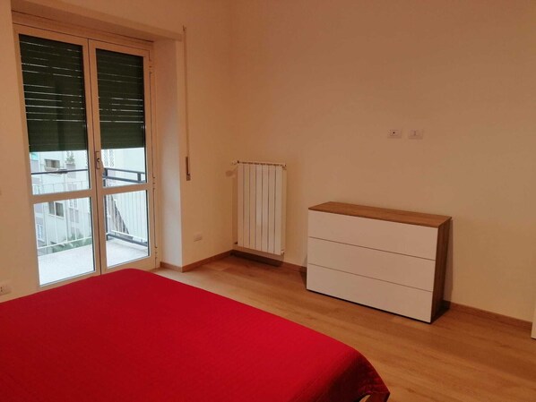 A bedroom with a bed, a dresser, a radiator, and a sliding glass door to the outside. - Slb House – Newly renovated accommodation, a 10-minute walk to the B1 Jonio subway station (Roma)