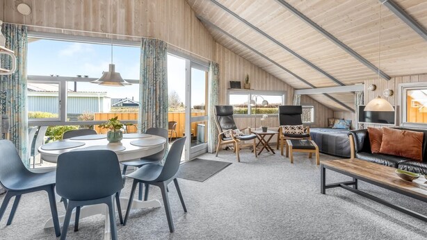 Ett rymligt vardagsrum med högt tak, ett matbord med stolar, en soffa och ett soffbord.