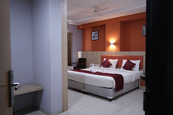 A hotel room with a bed, bedside table, nightstand, and a ceiling fan.