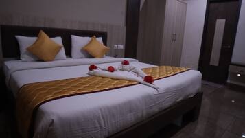 A neatly made bed with a golden quilt, white bedding, and decorative flowers.