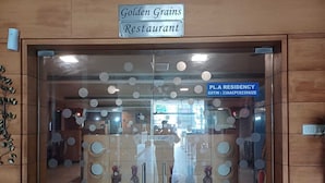 The entrance to the Golden Grains Restaurant with a sign above the door. - Hotel PL A Residency Tiruchirappalli (Tiruchirappalli)