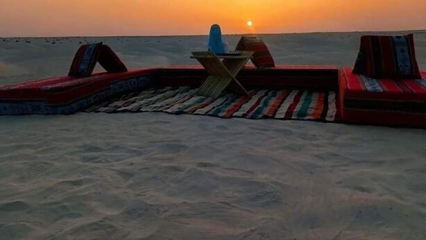 A beach setting with a sunset view, featuring a seating area with a table and chairs. - Douz Trek (Douz Sud)