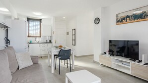 A modern apartment with a living room, dining area, kitchenette, and a TV. - Parque Don Jose Vista Teide by Interhome (Costa del Silencio)
