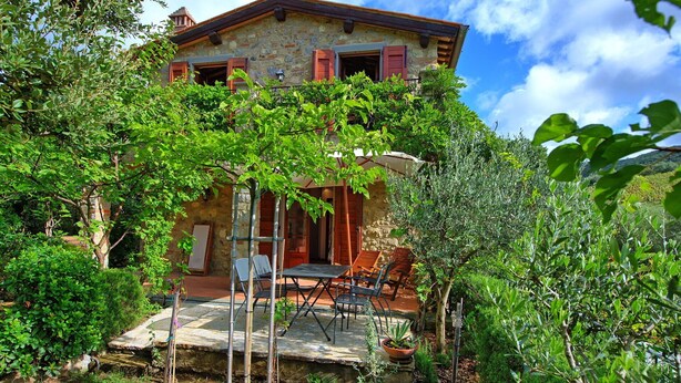Una casa de piedra con un patio, rodeada de exuberante vegetación.