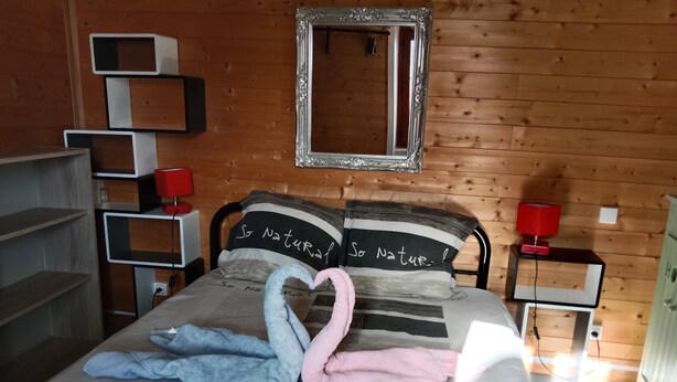 Une chambre à coucher avec un lit, un miroir, une lampe rouge et un mur en bois.
