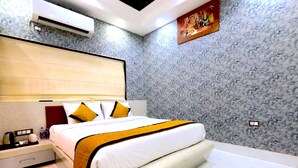 A modern hotel room with a large bed, a nightstand, a bedside table, an air conditioning unit, and a wall-mounted artwork. - THE MANTRA A LUXURY BOUTIQUE HOTEL (Patna)