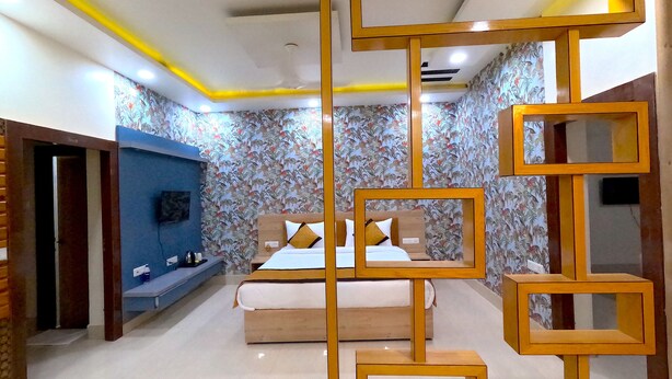 A bedroom with a bed, a blue wall unit, and a decorative wooden partition. - THE MANTRA A LUXURY BOUTIQUE HOTEL (Patna)