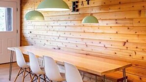 A wooden wall with the word "EAT" and a long table with white chairs. - Griz Inn Chic Condo - Mountain Views - Luxury Stay (Fernie)