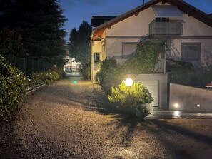 A gravel driveway leading to a house with a covered porch and a small garden area.