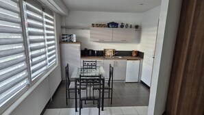A compact kitchen with a dining table and chairs, a microwave, and a sink.