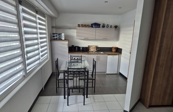 Una cocina compacta con una mesa y sillas, un microondas y un lavamanos.