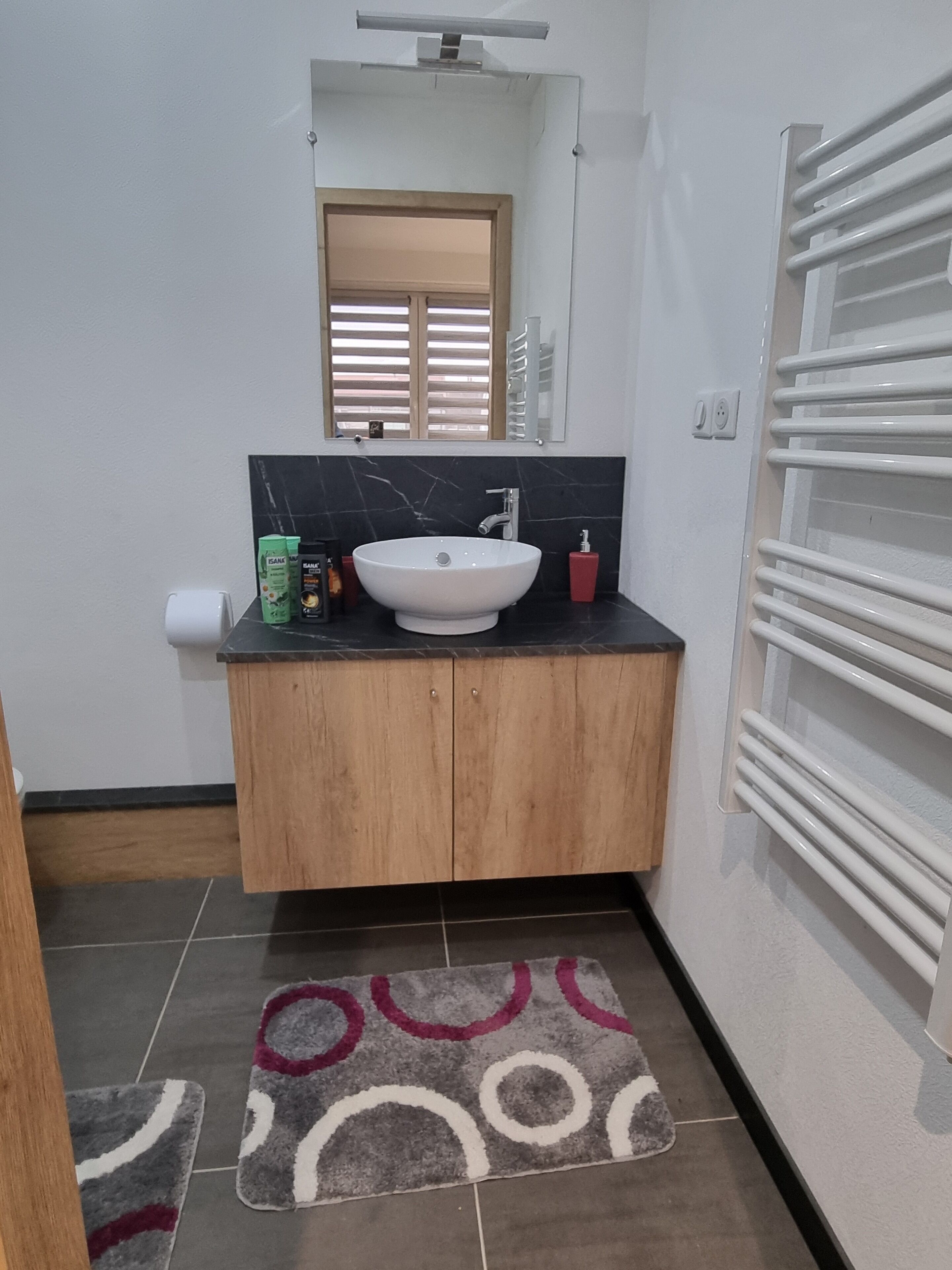 Un bagno con lavandino bianco, mobili in legno, uno specchio e un porta asciugamani.