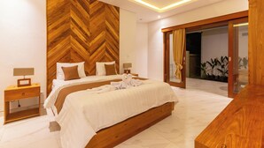A modern hotel room with a large bed, wooden headboard, and a wooden desk. - Sapta D'Villa Residence by Purely (Sukawati)