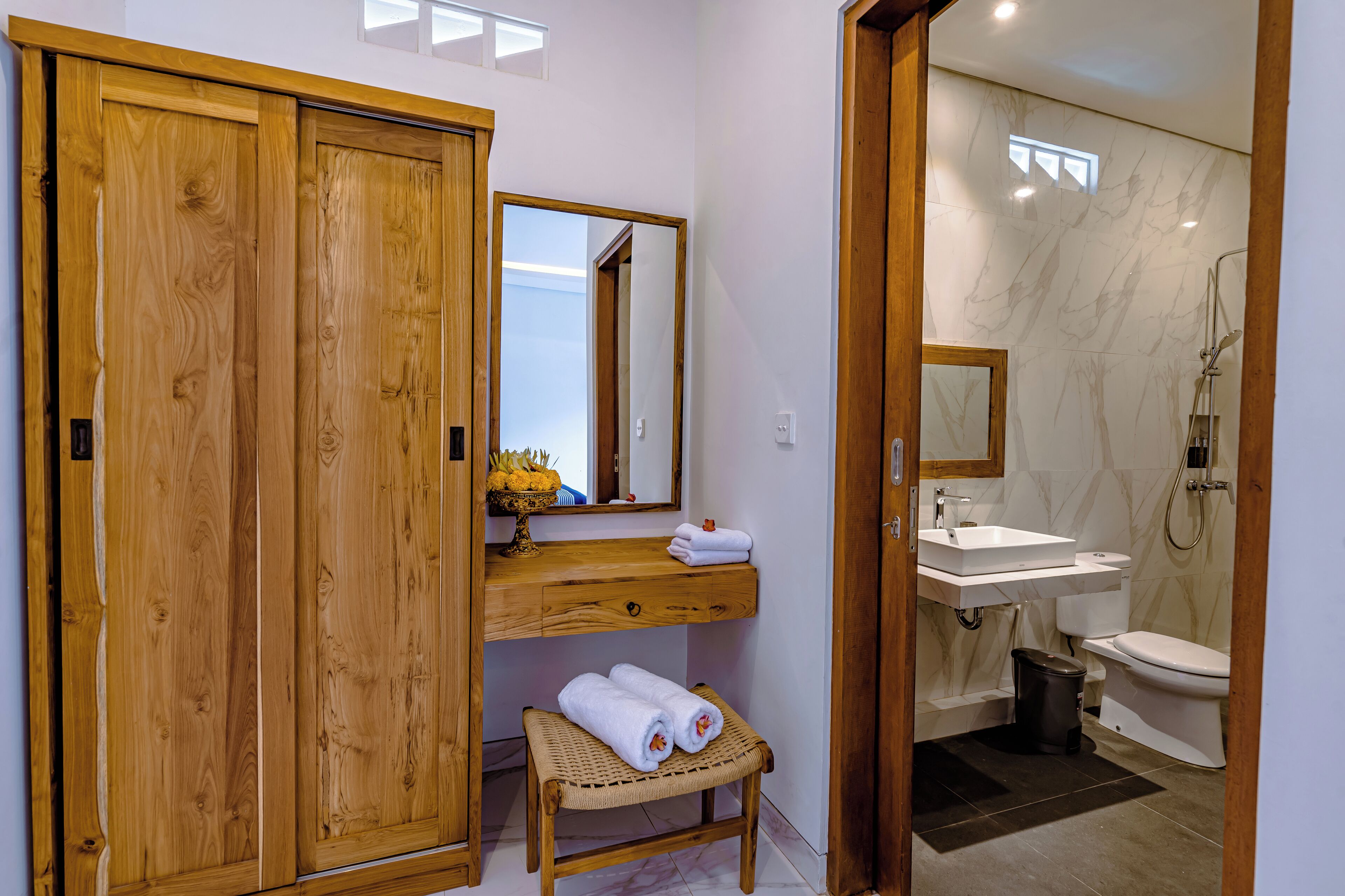 A bathroom with a wooden vanity, a mirror, a sink, and a toilet.