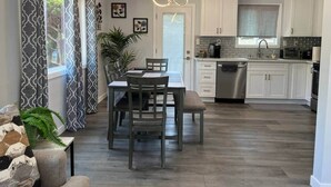A modern kitchen with white cabinets, a built-in oven, and a dining area with a table and chairs. - Adorable House with EV&Parking-Family Friendly (Culver City)