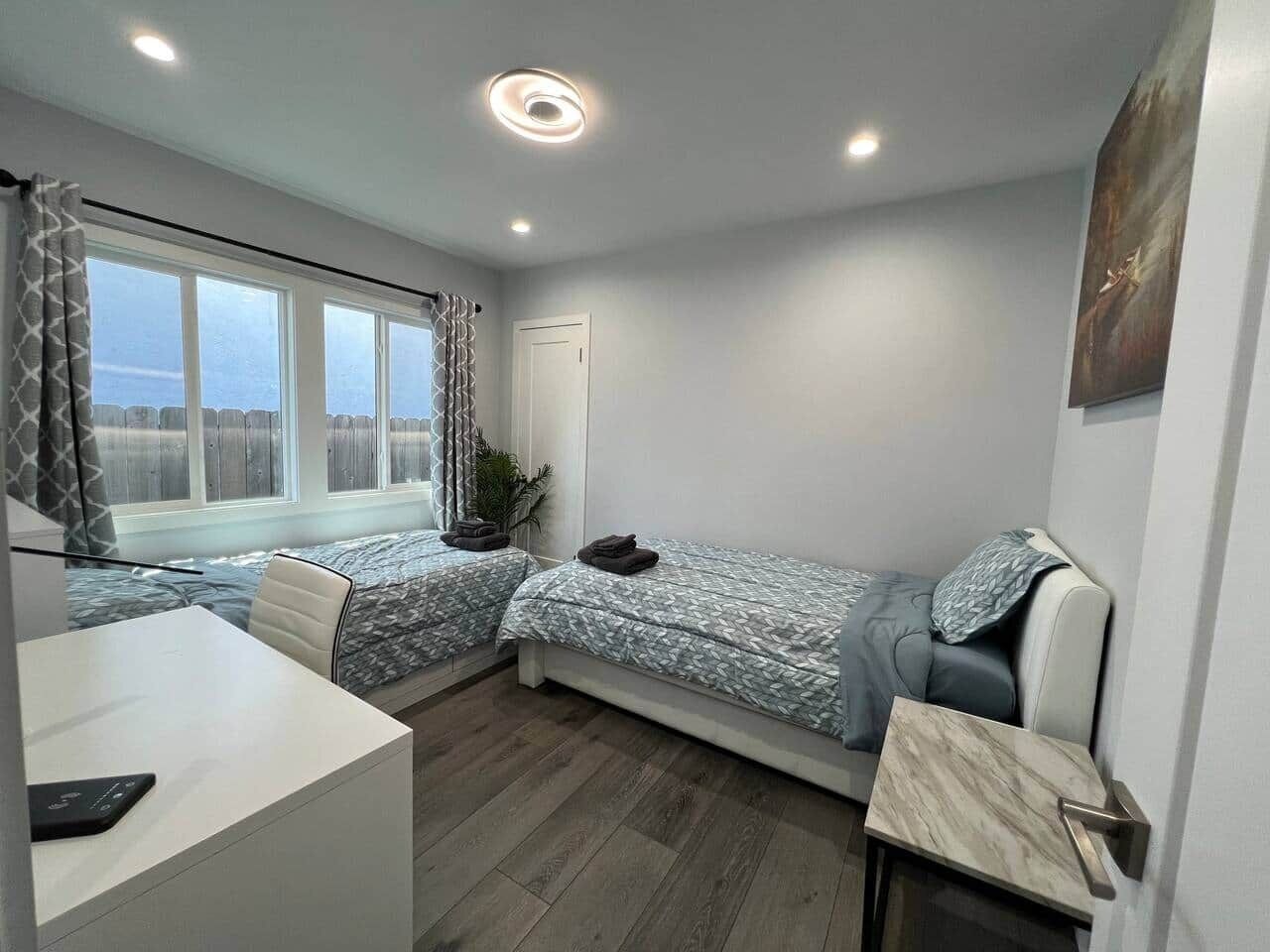 A compact room with two beds, a desk, and a window with curtains.