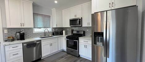 A modern kitchen with white cabinets, stainless steel appliances, and a dishwasher.