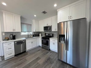 A modern kitchen with white cabinets, stainless steel appliances, and a dishwasher. - Cozywood 2BR Culver City: 6 Miles to SoFi Stadium (Culver City)
